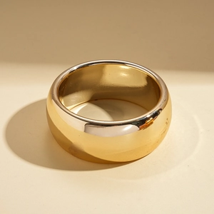Vue macro d'une large bague dorée polie aux parois épaisses et forme géométrique ronde