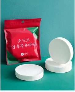 Macro shot of white compressed travel towel in red packaging against dark green background