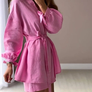 Détails d'un ensemble en lin rose avec col en V, taille nouée et manches bouffantes