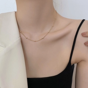 Gros plan détaillé d'un collier ras du cou doré à billes sur la clavicule d'une femme