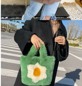 Detail of green plush tote with flower pattern and golden chain strap for shoulder wear