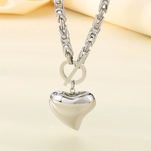 Close-up of silver hollow heart pendant on Byzantine chain with toggle clasp detail