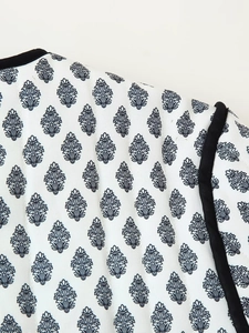 Detail of white quilted jacket featuring retro black leaf print and contrast piping