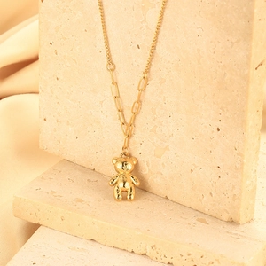 Detail view of 3D gold bear pendant on mixed chain over natural textured stone
