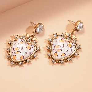 Macro detail of heart earrings with leopard print and sparkling crystals in vintage gold