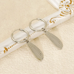 Silver stainless steel drop earrings with textured wing patterns on white frame