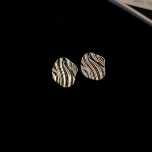 Minimalist silver wave earrings with irregular liquid metal texture on black background
