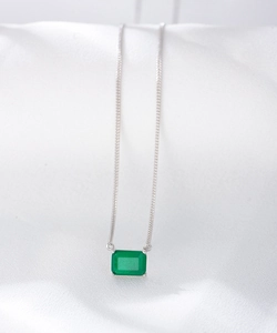 Macro detail of square emerald pendant on a fine silver chain with four-prong setting