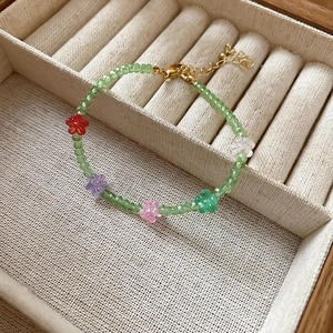 Macro detail of colorful crystal flower pendants and green faceted beads on gold necklace