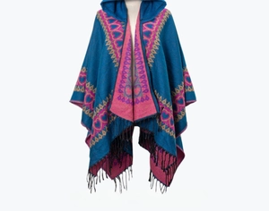 Détail d'un châle en tricot bleu et rose avec motifs cœurs, géométriques et franges
