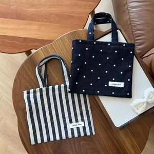 Detail of vintage canvas mini bags in striped and polka dot patterns on a wooden table