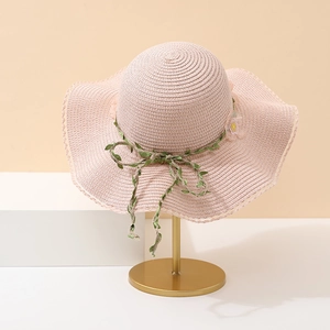 Vue détaillée d'un chapeau en paille rose avec décoration de vigne et accent floral jaune