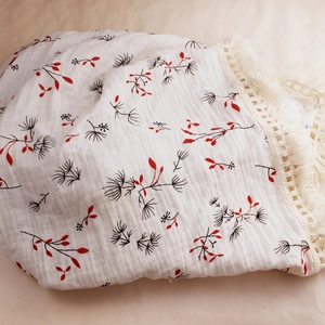 Close-up of double-layer cotton baby blanket with floral print and fringe details