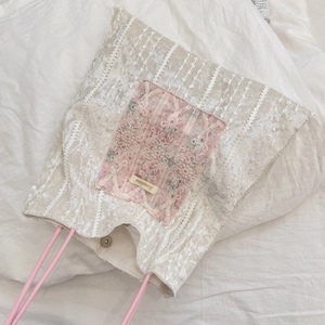 Détail du patchwork en dentelle florale et fermoir magnétique du sac en toile