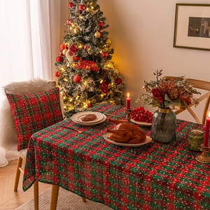 Christmas red and green plaid tablecloth with snowflakes shown in a cozy holiday dining scene