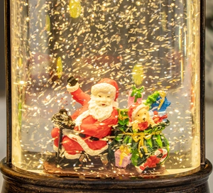 Close-up of a Christmas snow globe lantern featuring Santa Claus and golden glitter