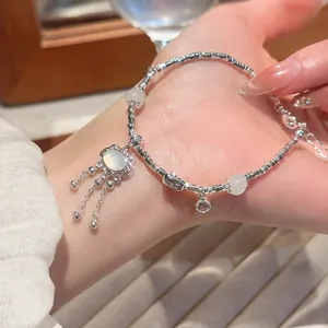 Elegant beaded bracelet with oval lock pendant and translucent gemstones on wrist