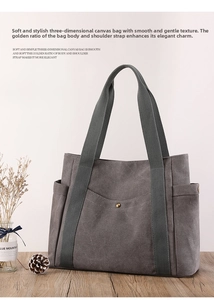 Detail of dark gray canvas tote bag with metal buckle pocket on a natural wooden surface