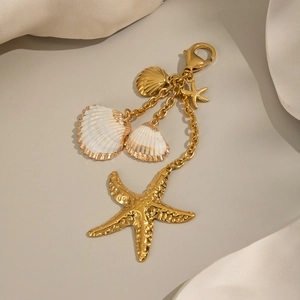 Golden starfish and shell bag charm with lobster clasp on elegant wavy background
