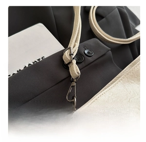 Close-up of durable dark grey metal hardware hook and beige lychee pattern leather bag