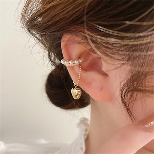 Dettaglio dell'ear cuff dorato con doppie file di perle e ciondolo a cuore