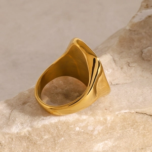 Detailed view of irregular gold dome ring placed on natural stone for elegant presentation