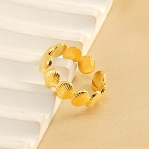 Adjustable golden shell open ring in stainless steel displayed on a white geometric prop