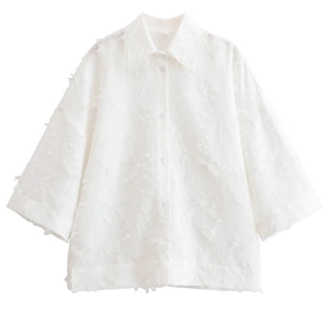 Détail de la chemise blanche avec franges en plumes et texture de tissu moelleux élégant