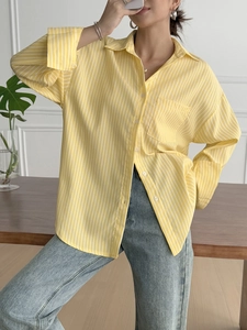 Detail of yellow and white striped long sleeve shirt with front pocket and collar