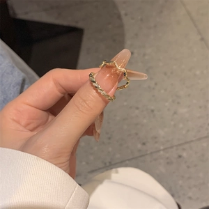Close-up of gold-plated twisted wave rings with zircon stones on female hand