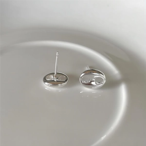 Close-up of 925 sterling silver pig nose stud earrings on a white ceramic plate