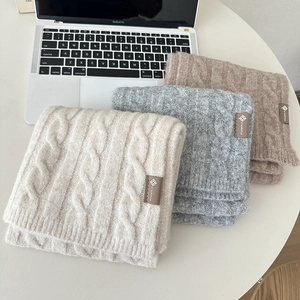 Detailed shot of beige, gray, and brown knitted wool scarves with premium leather patches