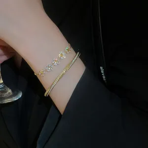 Close-up of gold plated star flower zircon bracelet and crisscross bangle on model wrist