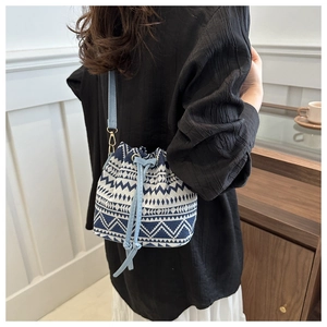 Detailed side view of ethnic blue geometric bucket bag with faux leather strap
