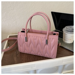 Detailed view of a pink quilted PU leather handbag with silver hardware on a desk