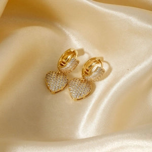 Elegant gold heart earrings with white cubic zirconia on champagne silk background