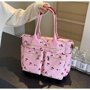 Detailed view of pink tote bag with cherry print and multi-functional zipper pockets