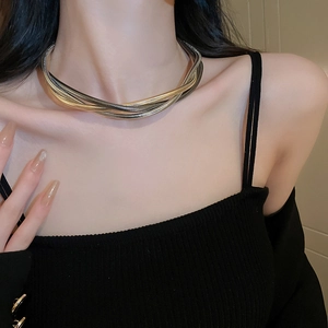 Close-up of a layered gold and silver snake chain necklace on a model's neck