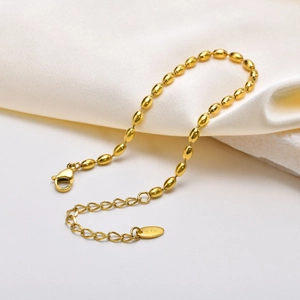 Macro shot of gold olive bead chain bracelet with K18 engraved tag and lobster clasp
