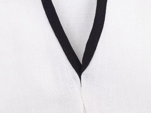 Macro shot of V-neckline with black contrast piping on white textured tweed fabric
