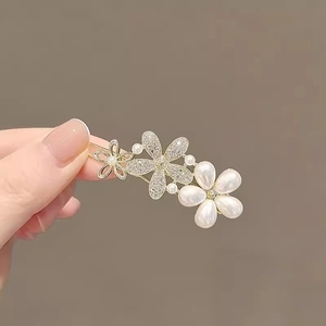 Macro detail of gold floral hair clip with white pearls and sparkling rhinestones