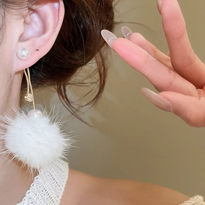 Close-up of winter style pearl and white faux fur pompom earrings with gold chain