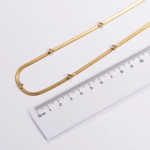 Detailed top view of a gold snake chain necklace with star pendant against a metric ruler