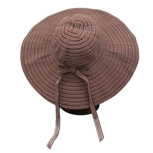 Detail of wide brim sun hat featuring brown and white stripes and a decorative bow
