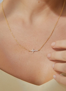 Close-up of elegant gold cross necklace with sparkling white zircons on a model neck