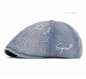 Detail view of denim beret with white Siyecao embroidery and distressed wash fabric