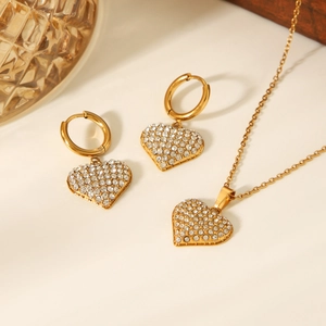 Detailed view of golden heart-shaped necklace and earrings set with sparkling rhinestones