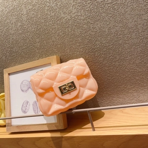 Mini bolso bandolera de gelatina rosa con rombos y cierre dorado sobre madera