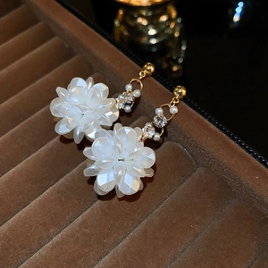 Dettaglio degli orecchini a fiore 3D con catene d'oro, perle e strass luccicanti