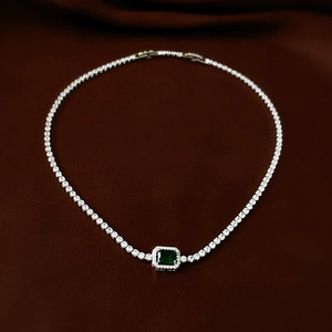 Detail of emerald cut green gemstone necklace with pavé diamond halo on velvet
